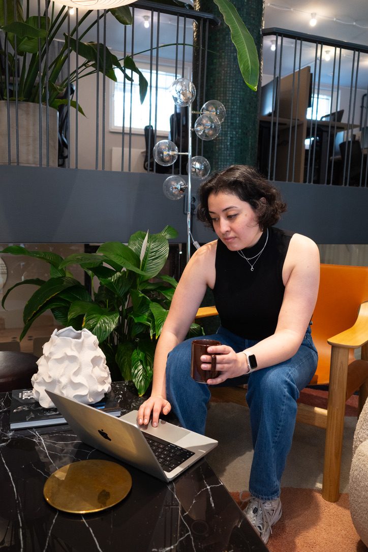 Cristina working on her laptop with a cup of coffee